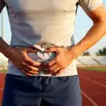 Coureur souffrant d une pubalgie main sur le pubis
